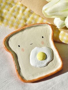 a piece of bread with an egg in the shape of a face on it next to flowers