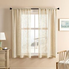 a living room scene with focus on the curtains and chair in front of the window