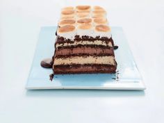 a piece of cake on a plate with chocolate icing and marshmallows