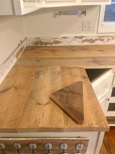 a wooden cutting board sitting on top of a counter in a kitchen next to an oven