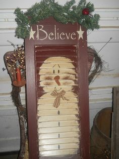 a wooden sign that says believe with a snowman on it's face and nose