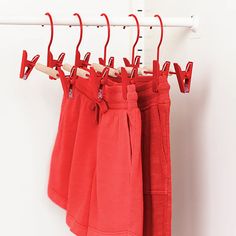 four red towels hanging on a rack in front of a white wall with clothes hangers