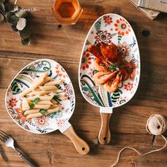 two serving spoons with food on them sitting on a wooden table next to other utensils