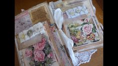 two open book pages with lace and flowers on them, sitting on top of a wooden table