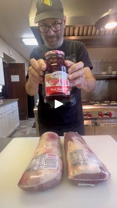 a man holding a jar of meat next to two loafs of bread on a counter