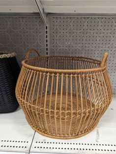 a wicker basket sitting on top of a white floor next to two black baskets