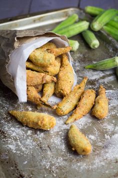 some fried food is sitting in a paper bag on a table next to asparagus