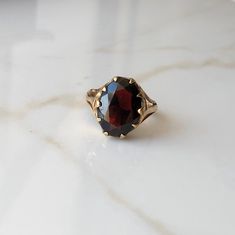 A Vintage 9 carat yellow gold Garnet ring. This beautiful piece holds a large deep red stone in a gold setting. CONDITION: Wear consistent with age and use. Please see photos for more detail. HALLMARKED 9 CARAT GOLD, ASSAYED IN LONDON 1977 STONE SIZE (SETTING): 14mm x 11mm  SETTING HEIGHT: 5mm BAND WIDTH: 2mm RING SIZE: US: 6 | UK: L 1/4 WEIGHT: 3.2 grams (UZZ) Vintage Oval Garnet Birthstone Ring, Gold Garnet Signet Ring For Formal Events, Gold Garnet Signet Ring For Formal Occasions, Yellow Gold Garnet Signet Ring With Gemstone, Antique Oval Yellow Gold Ruby Ring, Vintage Yellow Gold Garnet Birthstone Ring, Vintage Garnet Birthstone Ring In Yellow Gold, Classic Yellow Gold Garnet Birthstone Ring, Classic Garnet Birthstone Ring In Yellow Gold