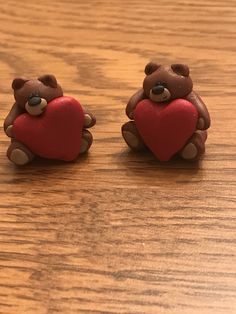 two brown teddy bears holding a red heart on a wooden table with wood grained surface