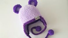 a purple and white knitted hat with pom poms