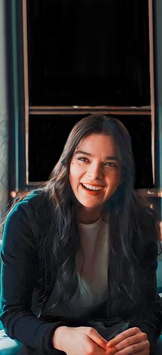 a woman sitting on top of a blue couch next to a window and smiling at the camera