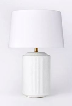 a white ceramic lamp with a gold metal base and a white shade on the top