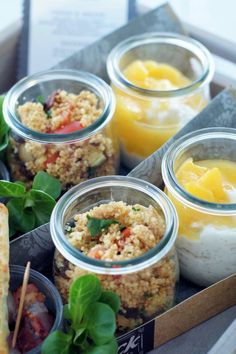 four jars filled with food sitting on top of a table