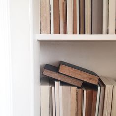 books are stacked on top of each other in a book shelf with white shelves behind them