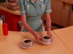 the woman is preparing two cups of coffee