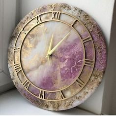 a clock with roman numerals on the face and purple marbled surface, in front of a window