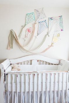 a white crib in a baby's room with lots of clothes hanging on the wall