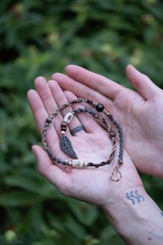 a person holding out their hand with two different bracelets on it and an arrow charm