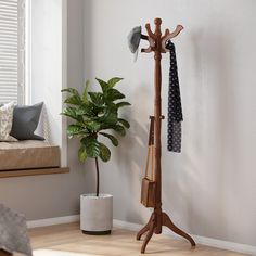 a coat rack with two coats hanging on it and a potted plant next to it