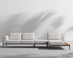 a white couch sitting on top of a wooden table in front of a gray wall