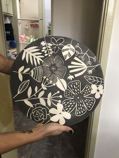 a person holding a black and white plate with flowers on it in their left hand