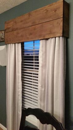 a window with white curtains and a wooden beam above it in a room that has blue walls