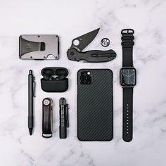 the contents of an apple watch laid out on a marble counter top with pens, scissors and other items