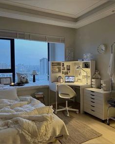 a bedroom with a bed, desk and window overlooking the cityscape in the distance