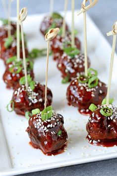 small appetizers with toothpicks are arranged on a white plate