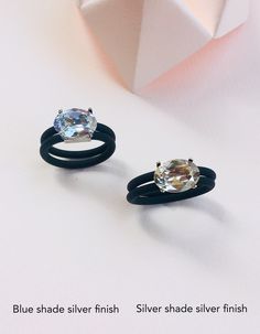 two black rings with an oval cut diamond on each one and a thin band around the ring