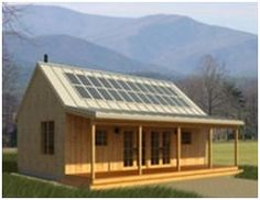 a small house with solar panels on the roof and windows, in front of mountains