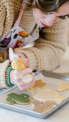 a woman is decorating cookies on a tray