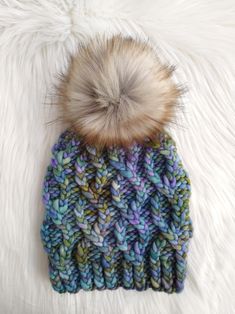 a multicolored knitted beanie with a fur pom