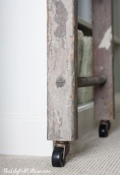 an old piece of metal with wheels on the floor next to a book shelf in a room