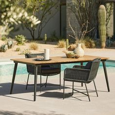 an outdoor table with two chairs and a vase on it next to a swimming pool