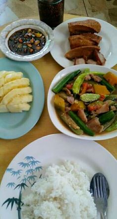 a table topped with plates and bowls filled with different types of food next to rice