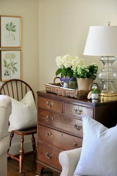 a living room filled with lots of furniture and flowers on top of a wooden dresser