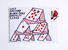 a red bird sitting on top of a pile of playing cards next to a postage stamp