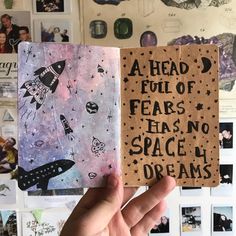 a hand holding up a book with an image of space shuttles and stars on it