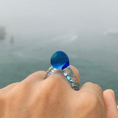 "Welcome to Hidden Glass Atelier! Glad you have found me  ✦ DESIGN    ✧ Ring crown: Center ball decoration made with transparent blue Murano glass    ✧ Ring band: signature Venetian \"zanfirico\" double twisted design with clear and blue transparent Murano glass.     ✧ Styling: This original unique ring with bold color combinations and contemporary design makes a lovely cocktail ring. It is easy to wear up or down with a casual outfit or for a special occasion.    ✧ Durability: All the glass jewelry pieces are tempered in a professional kiln for maximum durability.      ✧ Origin: This one-of-a-kind glass ring will be custom handmade for you by me from Murano Venice Italy - the very heart of glass art since the Middle Ages, with Murano glass, my original contemporary design, and the love of Unique Clear Crystal Ring For Gift, Unique Clear Crystal Ring As A Gift, Unique Blue Crystal Round Ring, Handmade Blue Crystal Ring With Unique Style, Light Blue Glass Jewelry For Gifts, Light Blue Glass Jewelry For Gifting, Handmade Unique Blue Crystal Ring, Blue Murano Glass Round Jewelry, Light Blue Glass Jewelry Gift