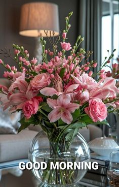 a vase filled with pink flowers sitting on top of a table next to a lamp