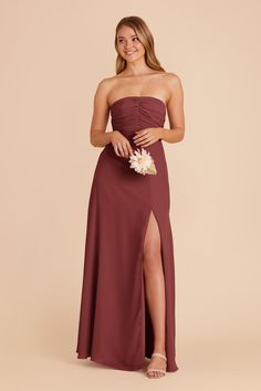 a bridesmaid in a strapless dress with a slited skirt and flower bouquet