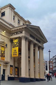 an old building with columns and lions on the front, along with people walking by