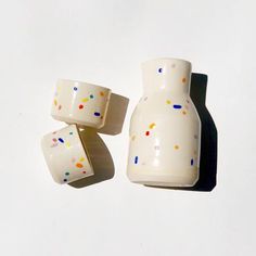 three white vases with sprinkles on them sitting next to each other