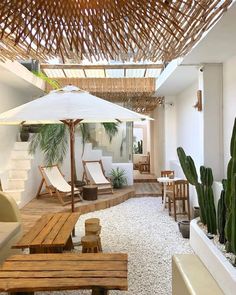 the inside of a house with an umbrella and chairs in it, next to a cactus