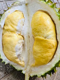 the inside of a durian fruit with two halves cut in half on a tile floor