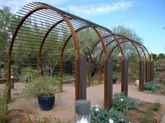 an outdoor garden area with many plants and flowers in the center, surrounded by wooden arbors