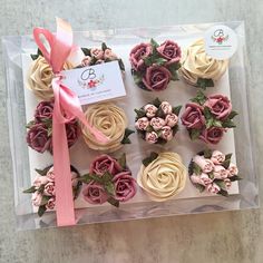 cupcakes with pink and white frosting in a clear box on a table