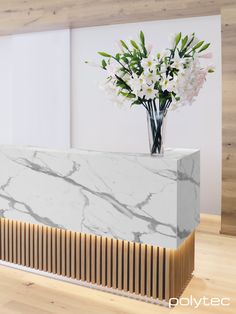 a vase with flowers in it sitting on top of a marble counter next to a wall