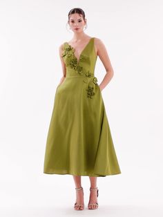 a woman wearing a green dress with flowers on it